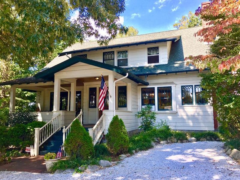 The front porch of Oakland Cottage with an American flag, Asheville NC